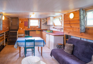 Interieur van woonboot Le Bateau du Lac Privé in België met keuken, eettafel en bank.