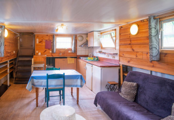 Vista interna di Le Bateau du Lac Privé, houseboat in Belgio, con cucina, tavolo e divano.