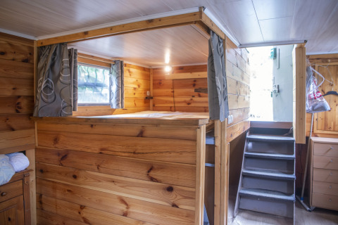 Houten interieur van houseboat Le Bateau du Lac Privé in België met bed, trap en ramen.