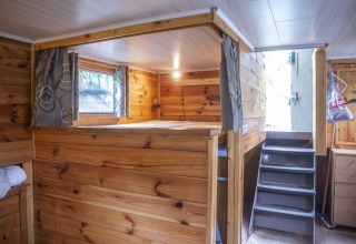 Houten interieur van houseboat Le Bateau du Lac Privé in België met bed, trap en ramen.