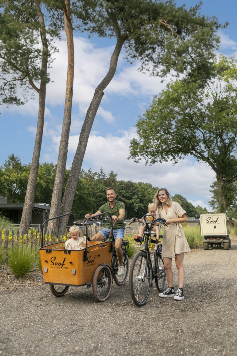 Gezin fietst op een zonnige dag bij Soof Retreats vakantiepark in Utrecht, Nederland, omringd door natuur.