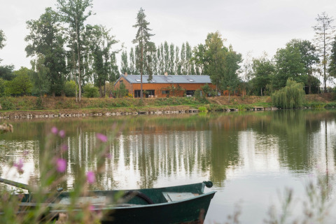Le Bateau du Lac Privé woonboot aan een rustige vijver, omgeven door bomen en natuur in België.
