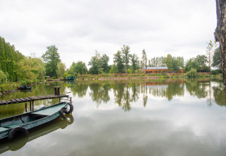 Woonboot aan een rustige oever met aanlegsteiger en bomen, Le Bateau du Lac Privé in België.
