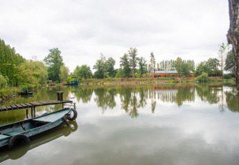 Hus på søbredden med båd ved kajen og træer, set ved Le Bateau du Lac Privé i Belgien.