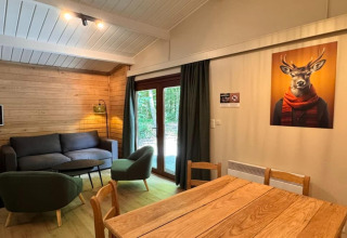 Vista interior del chalet 'OREE DU BOIS' en Bélgica, sala de estar acogedora y cuadro de un ciervo con bufanda.
