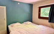 Slaapkamer in chalet OREE DU BOIS in België met twee bedden, groene muur, raam en witte kast.