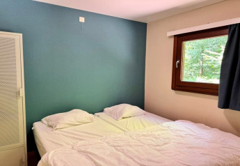 Slaapkamer in chalet OREE DU BOIS in België met twee bedden, groene muur, raam en witte kast.