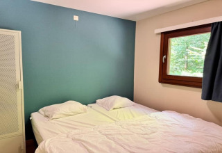 Dormitorio en el chalet OREE DU BOIS en Bélgica con dos camas, pared verde, ventana y armario blanco.