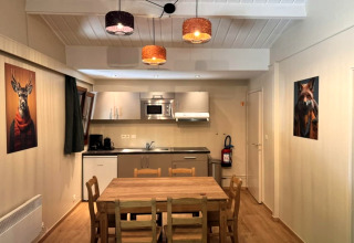 Binnenzicht op keuken en eetplaats van chalet OREE DU BOIS in België met dierenportretten aan de muren.
