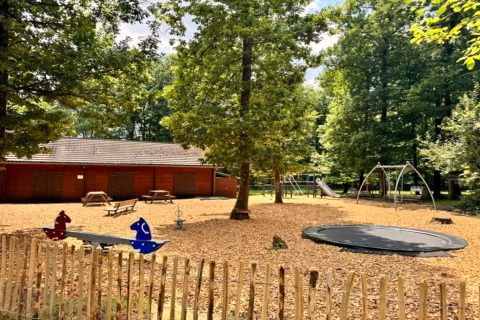 Speelplein aan chalet OREE DU BOIS in België met schommels, glijbaan, trampoline en houten chalet.