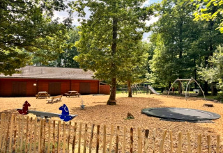 Speelplein aan chalet OREE DU BOIS in België met schommels, glijbaan, trampoline en houten chalet.