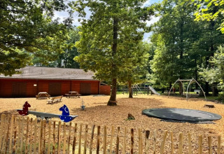 Parque infantil en el chalet OREE DU BOIS en Bélgica con columpios, tobogán, trampolín y cabaña de madera.