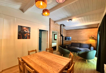 Het interieur van chalet OREE DU BOIS in België, met houten wanden, eettafel en gezellige zithoek.