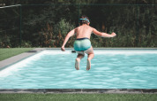 A child jumps into a swimming pool at Holiday Park Ardinam 1 in Belgium, surrounded by green nature.