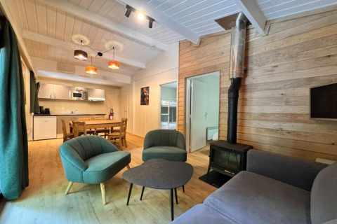 Acogedora sala de chalet con estufa de leña, cocina moderna y comedor en OREE DU BOIS, Bélgica.