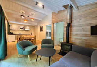 Acogedora sala de chalet con estufa de leña, cocina moderna y comedor en OREE DU BOIS, Bélgica.
