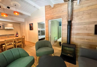 Woonkamer van chalet OREE DU BOIS in België met houtkachel, eettafel, en moderne open keuken.