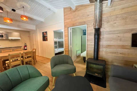 Acogedora sala de estar en el chalet OREE DU BOIS en Bélgica con estufa de leña, comedor y cocina abierta.
