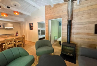 Acogedora sala de estar en el chalet OREE DU BOIS en Bélgica con estufa de leña, comedor y cocina abierta.