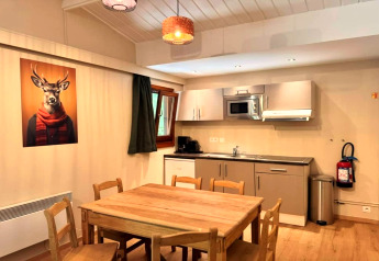 Moderne keuken in chalet 'OREE DU BOIS' in België met houten meubels en grappig hertenschilderij.