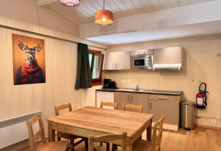 Cocina moderna en el chalet 'OREE DU BOIS' de Bélgica con muebles de madera y cuadro divertido de ciervo.