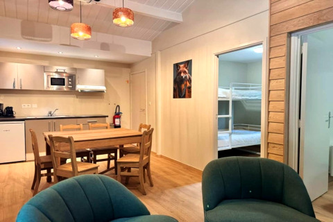Interieur van chalet OREE DU BOIS in België, met eettafel, keuken en zicht op stapelbedden.