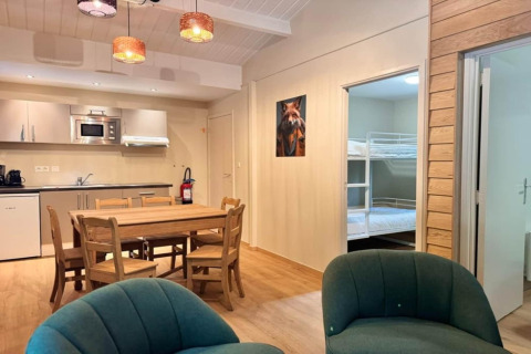 Interior del chalet OREE DU BOIS en Bélgica, mesa de comedor, cocina y literas a la vista.