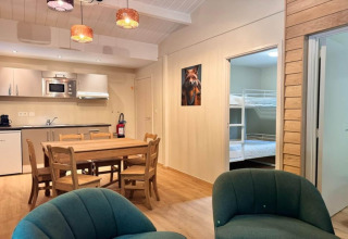 Interior del chalet OREE DU BOIS en Bélgica, mesa de comedor, cocina y literas a la vista.