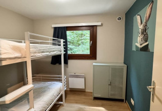 Habitación con litera, ventana con cortina, armario y cuadro de conejo, chalet OREE DU BOIS, Bélgica.