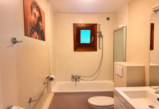 Baño color beige en el chalet OREE DU BOIS en Bélgica, con bañera, ventana y cuadro de erizo en la pared.