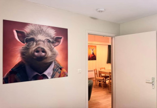 Foto interior del chalet OREE DU BOIS en Bélgica mostrando un retrato gracioso de un cerdo con traje.