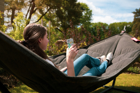 Vrouw ontspant in een hangmat met een drankje in de tuin van Soof Retreats vakantiepark Utrecht, Nederland.