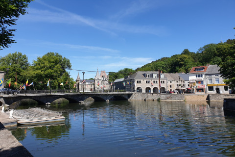 Bridge over a river at Holiday Park Ardinam 1 in Belgium, with colorful flags and charming historic buildings.