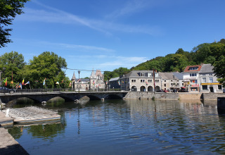 Ponte su un fiume al Holiday Park Ardinam 1 in Belgio, con bandiere colorate ed edifici caratteristici.