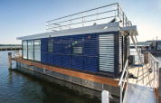 Moderne Hausboot 'Floating Houses Blue Active' am Steg in Ribnitz-Damgarten, Deutschland, bei Sonnenschein.