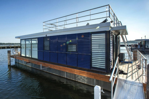 Moderne blå husbåd 'Floating Houses Blue Active' fortøjet ved en dok i Ribnitz-Damgarten, Tyskland.