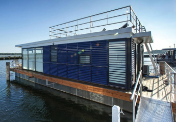 Moderne Hausboot 'Floating Houses Blue Active' am Steg in Ribnitz-Damgarten, Deutschland, bei Sonnenschein.