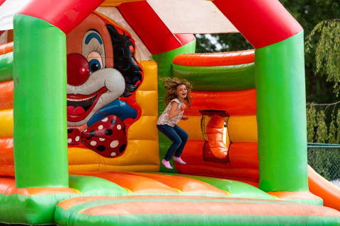 Una bambina salta su un colorato castello gonfiabile a tema clown al Holiday Park Ardinam 1, Belgio.