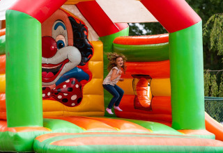 Una bambina salta su un colorato castello gonfiabile a tema clown al Holiday Park Ardinam 1, Belgio.