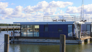 Modern houseboat named 'Luisa' docked in Ribnitz-Damgarten, featuring large windows and a rooftop deck.