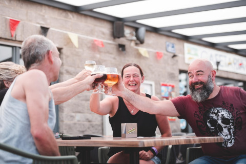 Vrienden proosten met drankjes bij Holiday Park Ardinam 1 mobilhome in België, lachend en genietend.