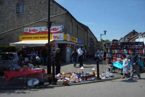 Straatmarkt voor Epicerie Chez Nancy in België met kraampjes en kleurrijke producten uitgestald.