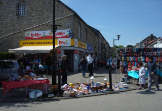 Straatmarkt voor Epicerie Chez Nancy in België met kraampjes en kleurrijke producten uitgestald.