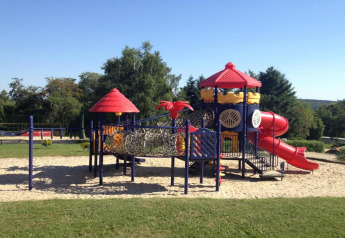 Playground with slides and climbing structures at Holiday Park Ardinam 1 mobile home in Belgium on a sunny day.