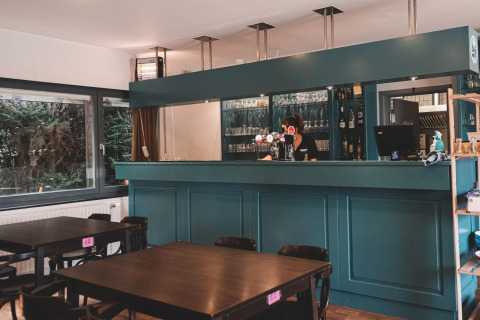 Bar moderno e sala da pranzo a Holiday Park Ardinam 1 in Belgio, con tavoli in legno e bancone verde.