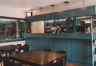 Moderne Bar und Essbereich im Holiday Park Ardinam 1, Belgien, mit Holztischen und grüner Bar.