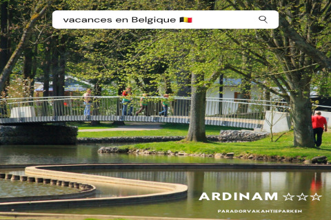 Photo of Holiday Park Ardinam 1 in Belgium, showing a scenic bridge, trees, pond, and people enjoying a walk.