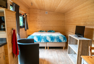 Gemütliches Mobilheim in Belgien mit Holzinterieur, Doppelbett, TV und modernen Annehmlichkeiten.