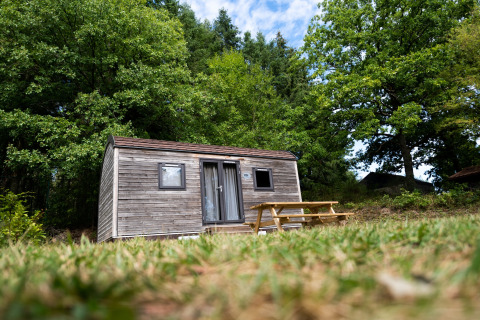 Stacaravan Holiday Park Ardinam 1 in België, omringd door bomen met een houten picknicktafel buiten.