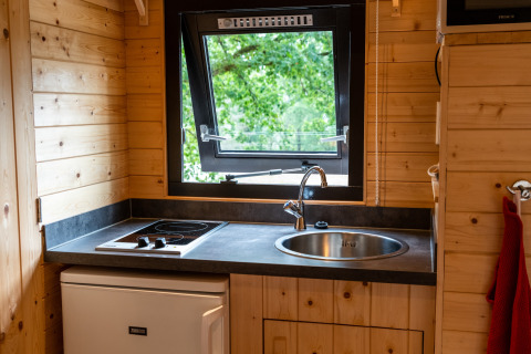 Kleine kitchenette met kookplaat, gootsteen en open raam in een mobiel huis bij Holiday Park Ardinam 1, België.